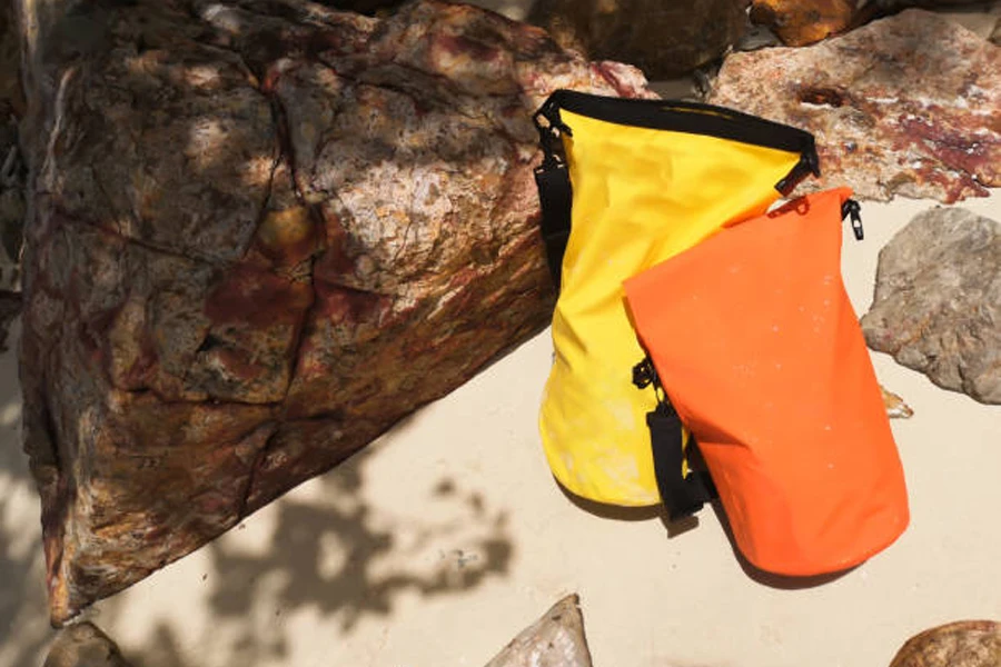 Yellow and orange roll-top dry bags on sand