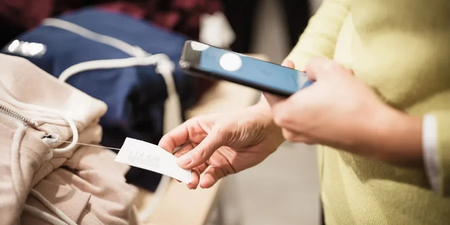 衣料品店の若い女性。買い物、服の選択、携帯電話の使用