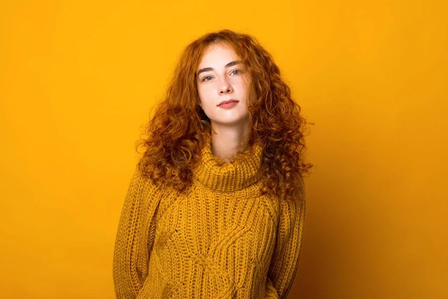 Young woman standing against yellow background