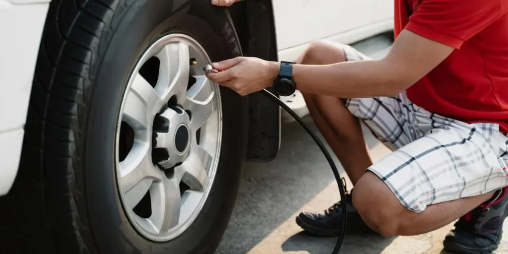 A man inflating the tire of a white vehicle