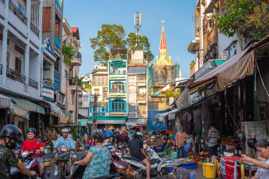 a small market street with a Catholic church in the background in Cholon historic district