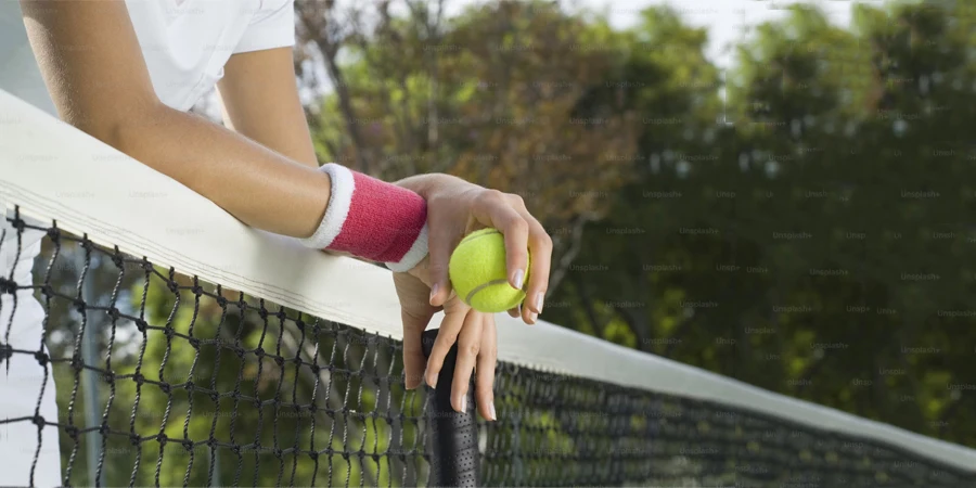 a woman holding a tennis ball and racquet on a tennis court