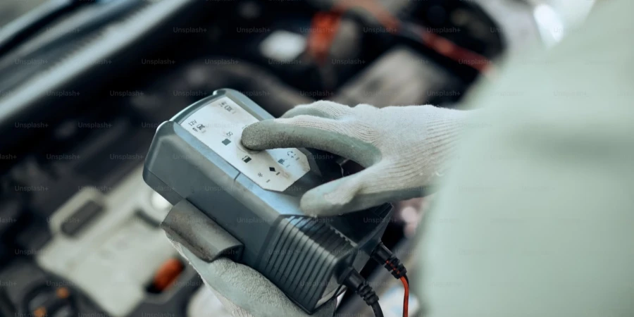 close up of auto repair man using diagnostic work tool while checking car battery