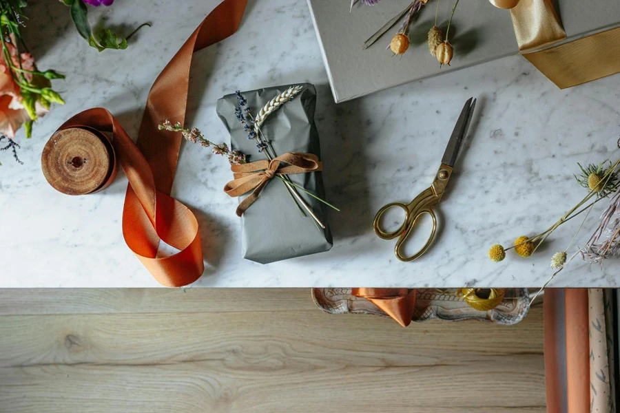 gift-wrapped in gray paper beside orange ribbon and golden scissors