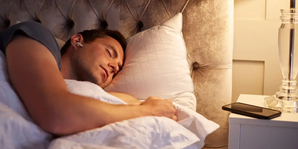 Person lying on their side in bed wearing earbuds