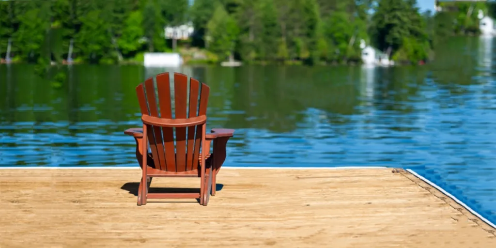 single Adirondack chair on a wooden dock facing the sea