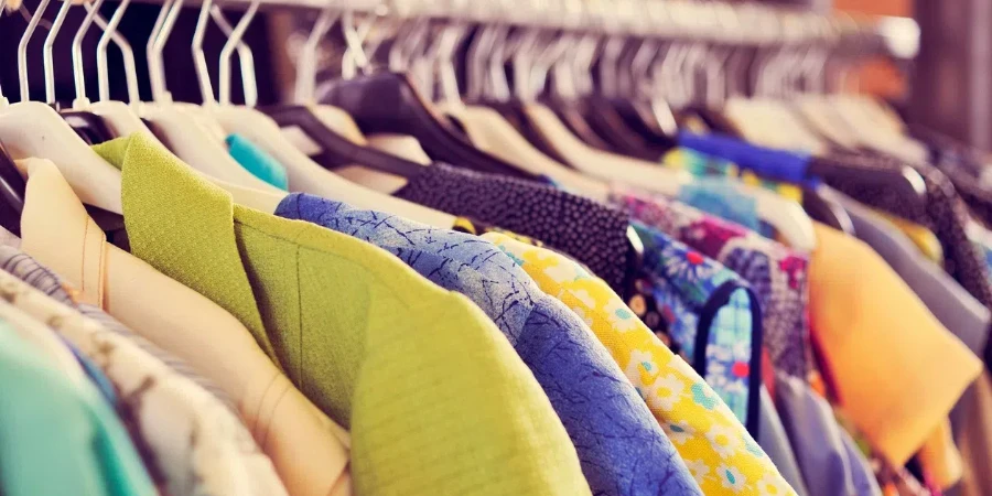 some used clothes hanging on a rack in a flea market