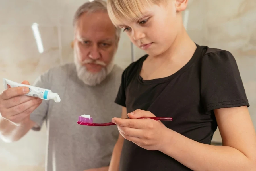 A Grandfather Putting Toothpaste on His Granddaughter Toothbrush