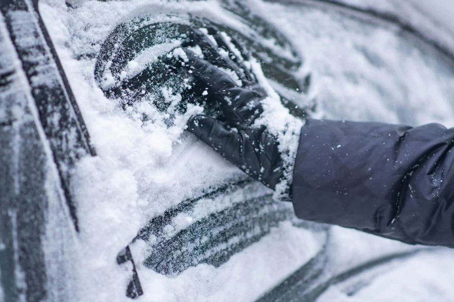 A Person Removing Snow from a Car Window