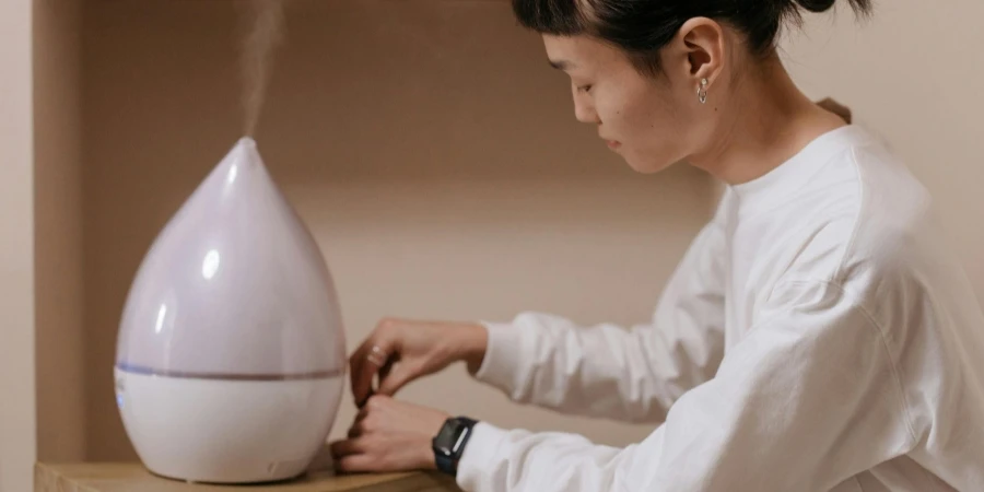 A Woman in White Sweater Sitting Beside the Wooden Table with Humidifier