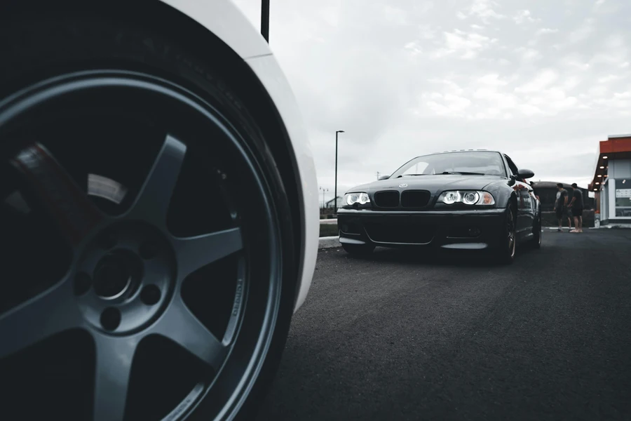 A black car with white rims on the road