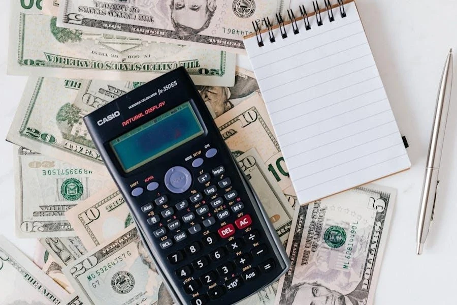 A calculator and a notepad on a stack of bills