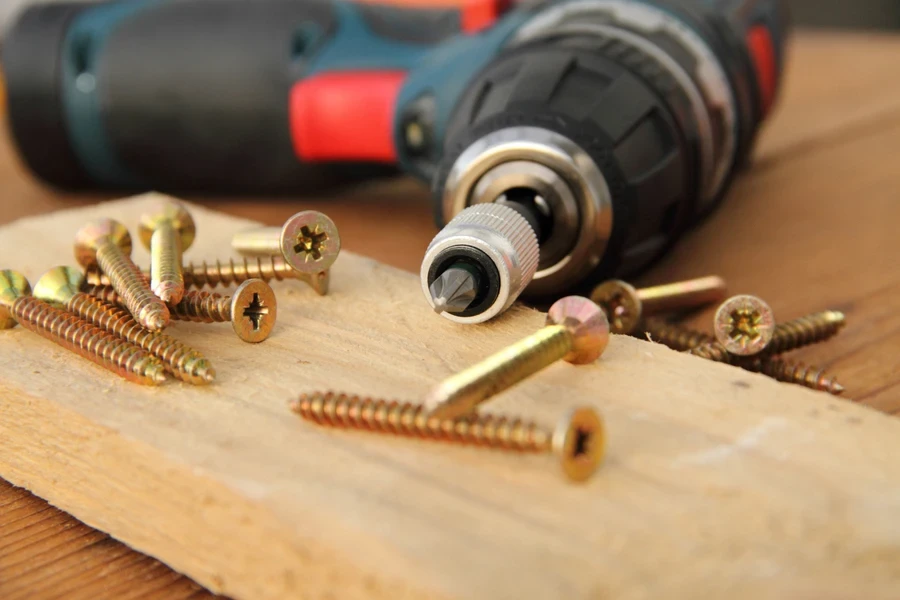 A cordless screwdriver with screws and bits on a workbench