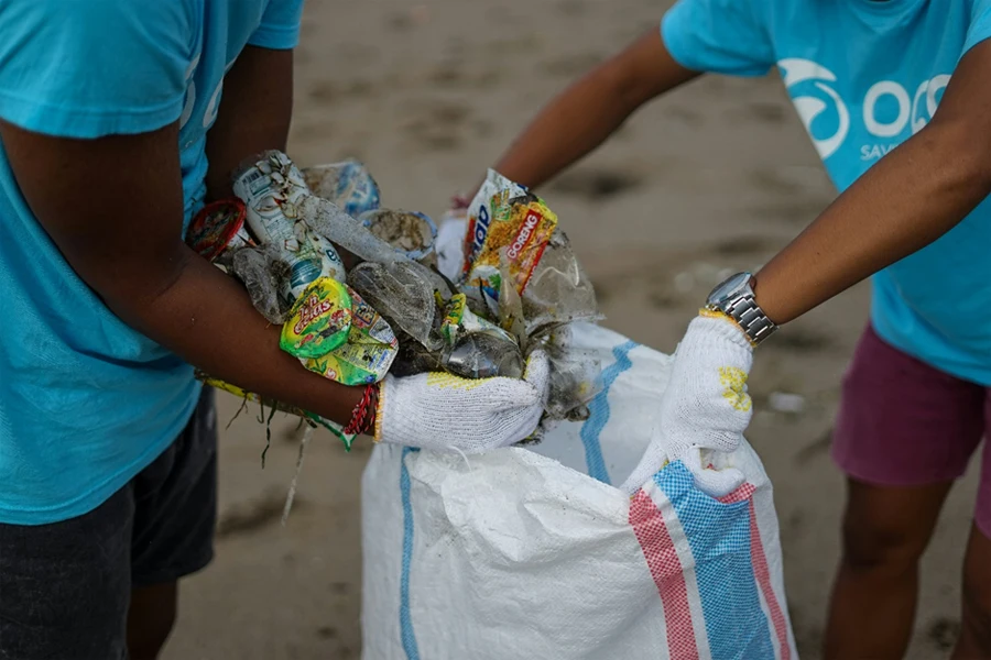 A couple of people holding garbage bags