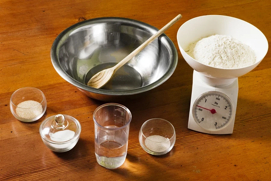 A kitchen scale, mixing bowl, and measured ingredients in containers