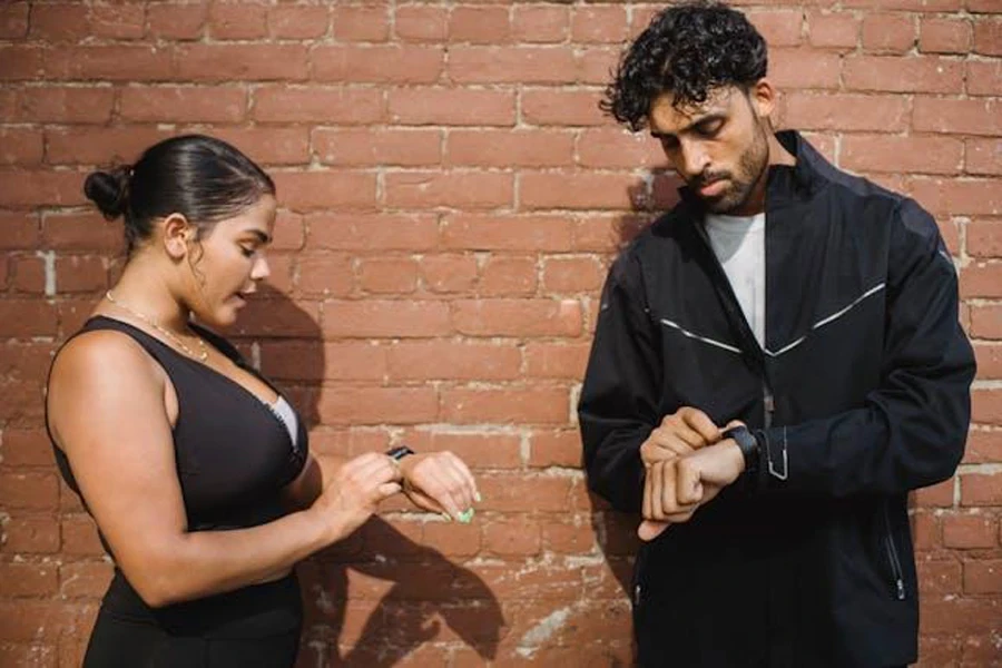 A man and woman looking at their wristwatches