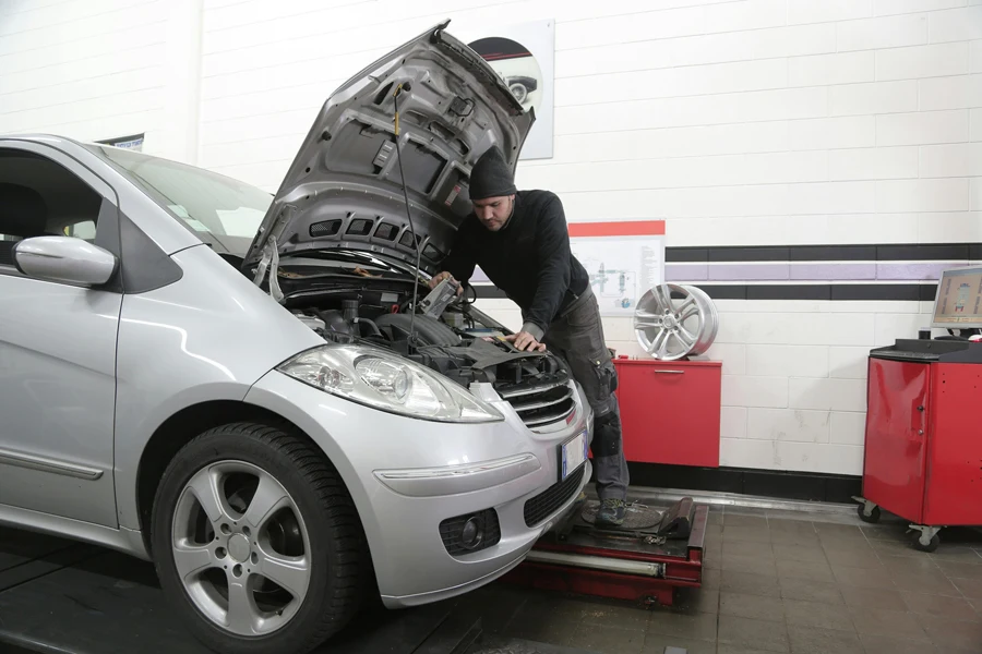 A person servicing a car with the hood open