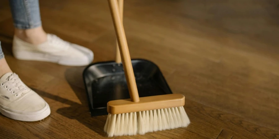 A person stands beside brown broom