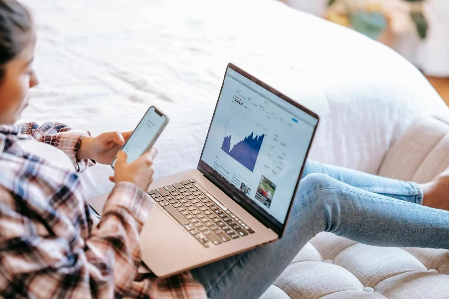 A person using smartphone against laptop