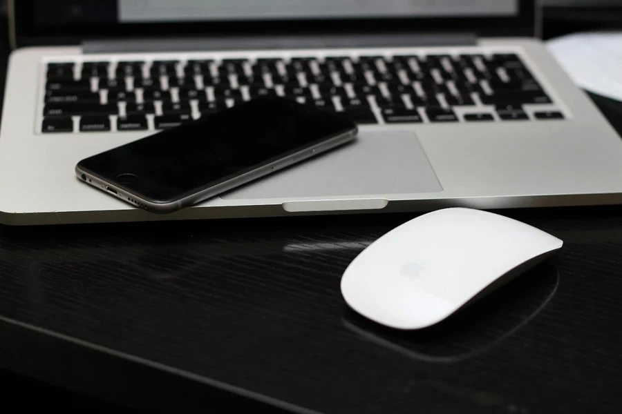 A pic of a mouse in front of a phone kept over a laptop