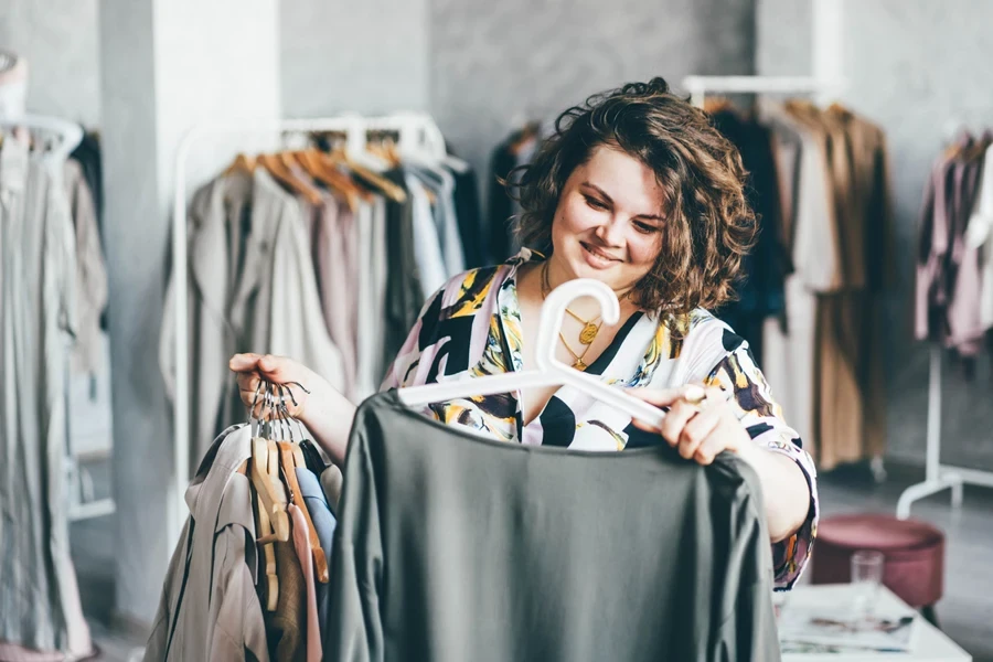 A plus-sized woman choosing dresses in a store