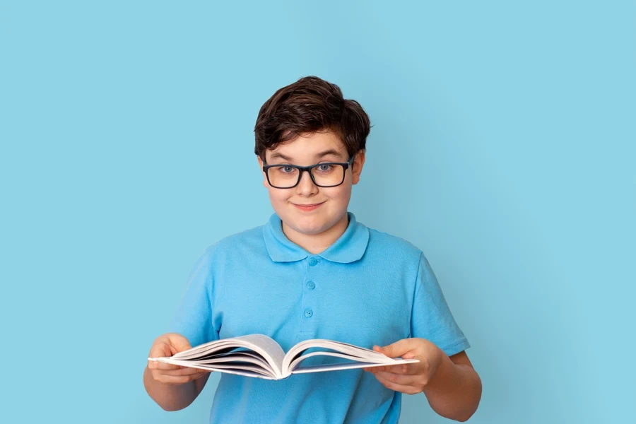 A schoolboy in a blue polo shirt with an open book