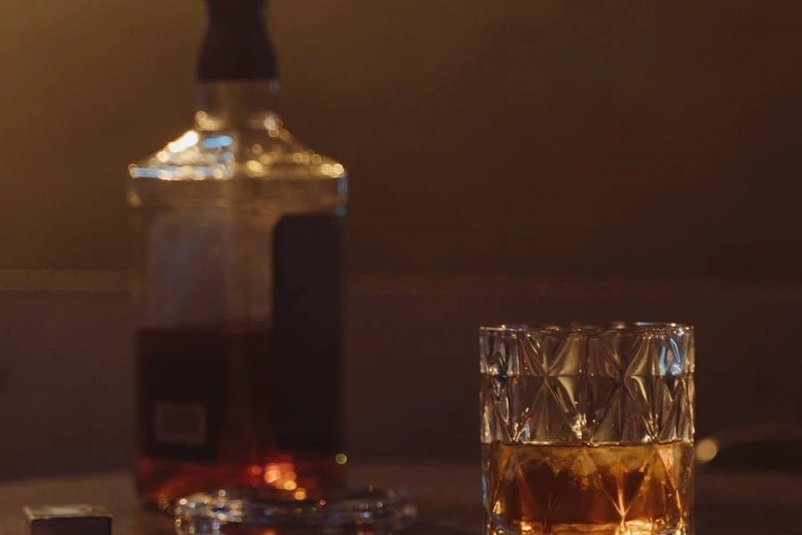 A whisky bottle beside a rocks glass