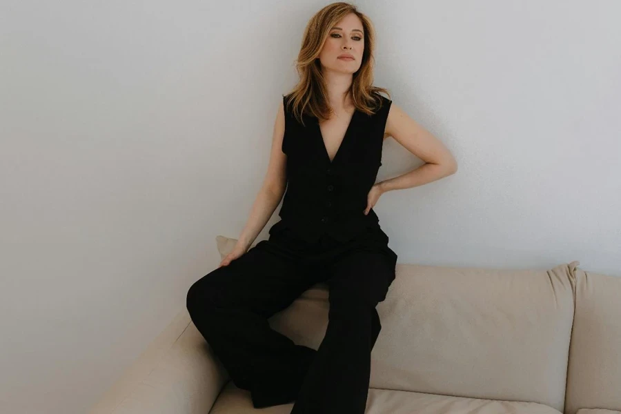 A woman in black jumpsuit sitting on a couch