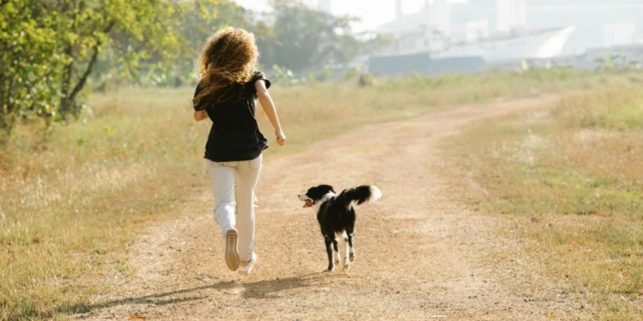 A woman running with a dog on path in park