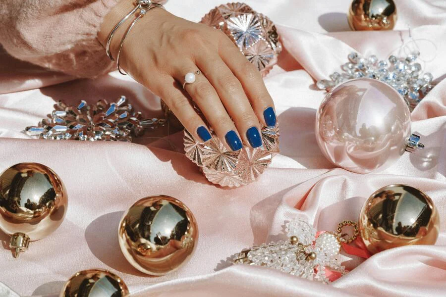 A woman’s hands in lip gloss blue manicure