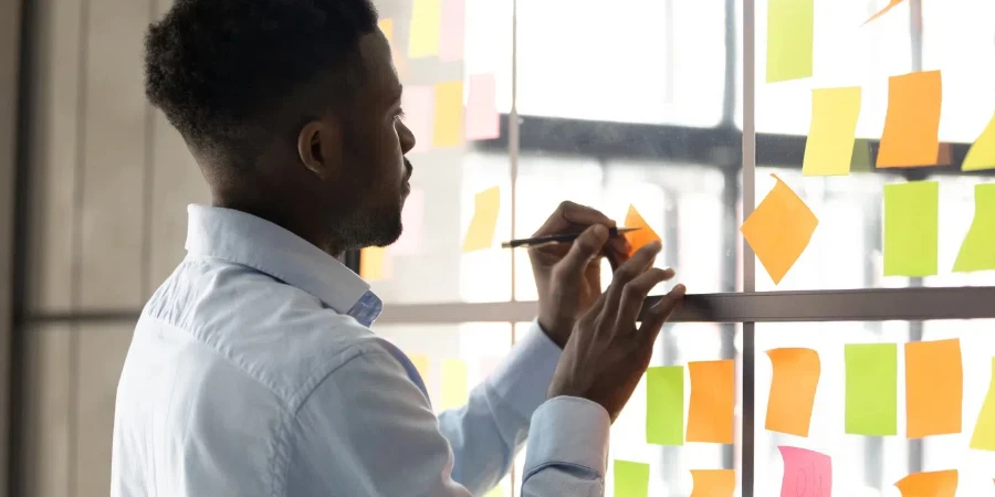 African American male employee write on colorful sticky notes