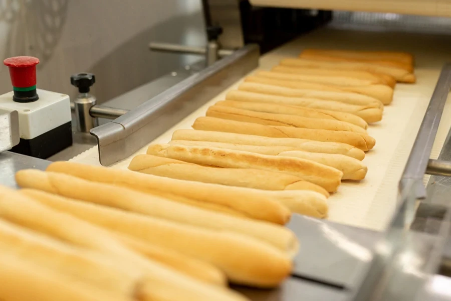 Baked baguettes on a conveyor belt in an industrial bakery