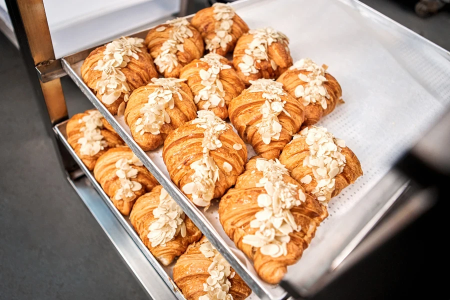 Bakery shop production croissants with almond flakes on tray top view