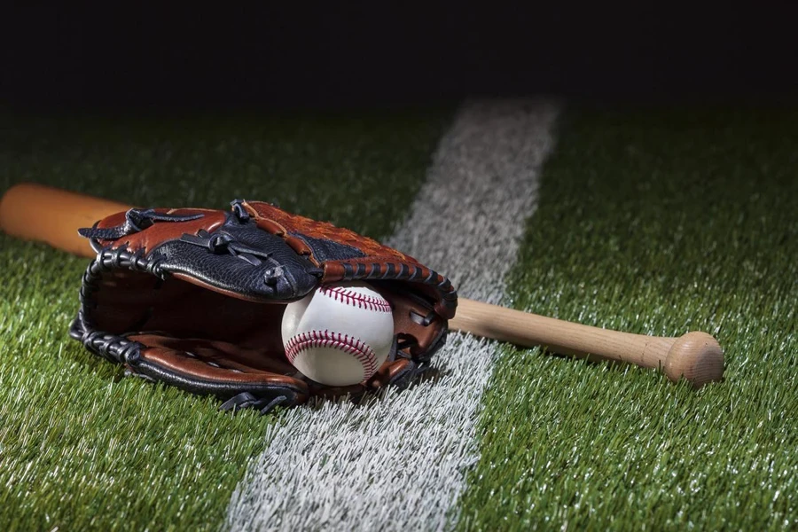 Baseball in a mitt with bat at low angle view on a field with stripe and dramatic lighting and dark background