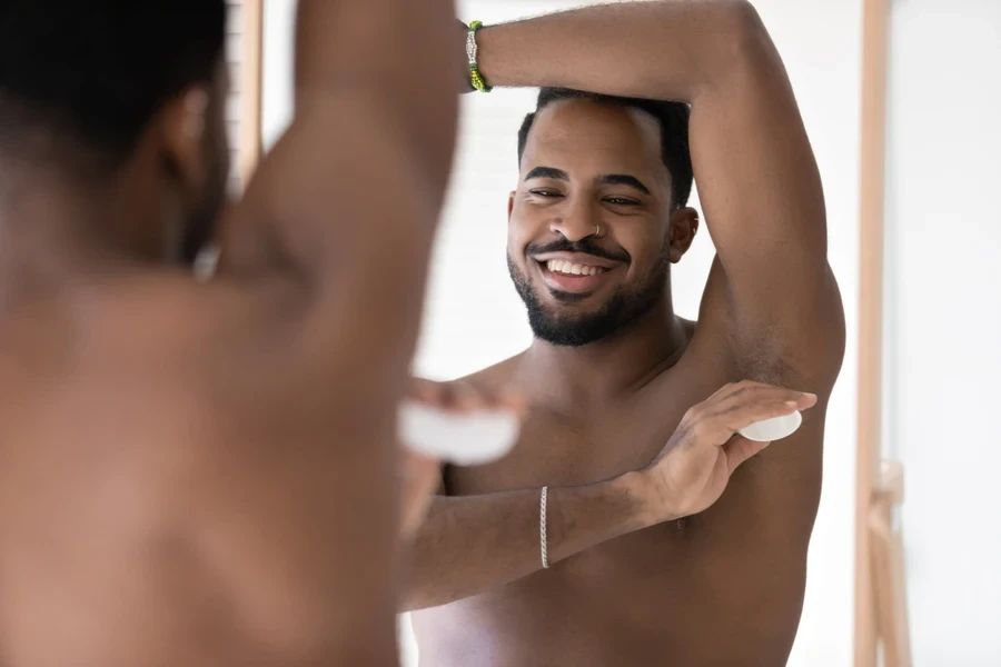 Black man applying deodorant on armpit