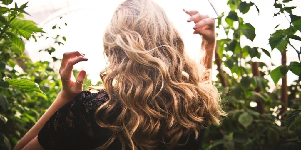 Blonde woman standing between green plants