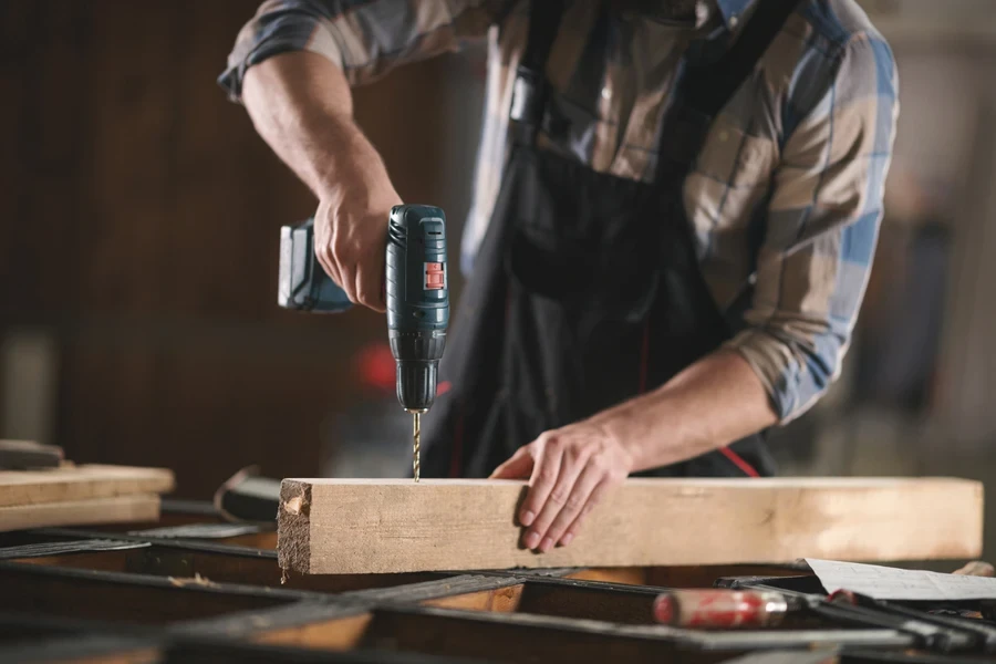 Carpenter working with an electric drill and wood