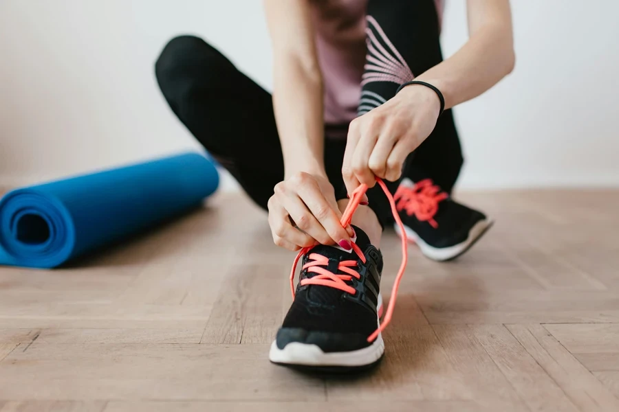 Crop young sportswoman tying shoelaces on sneakers