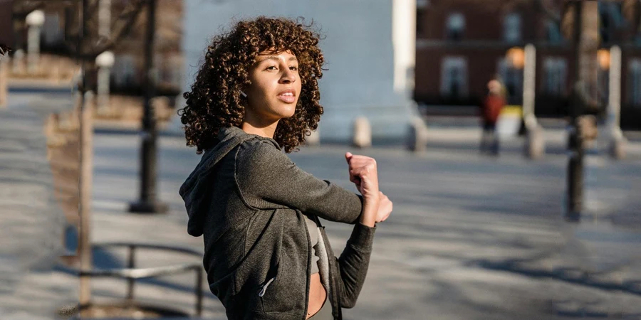 Ethnic woman stretching arms on street