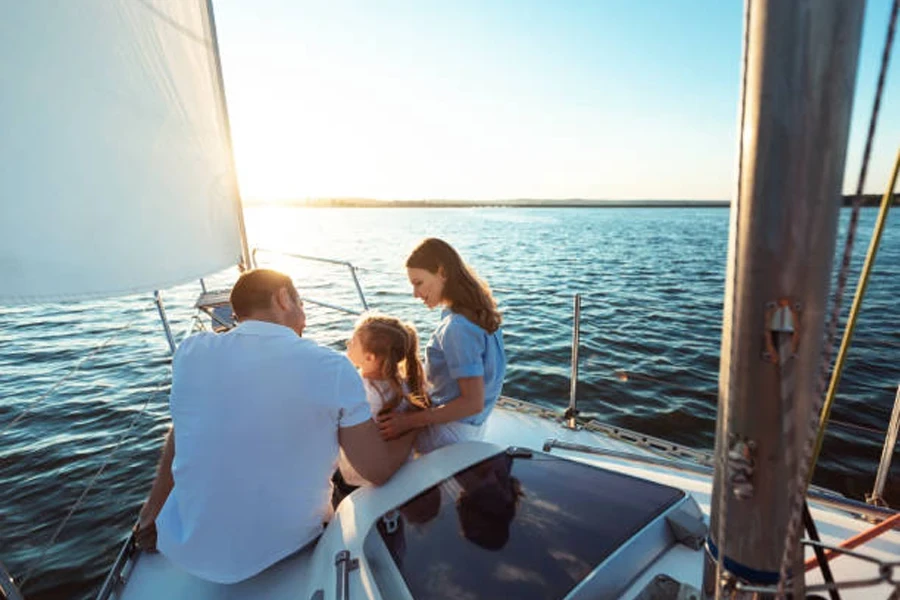 Family of Three Sitting on Yacht Deck Sailing in Sea