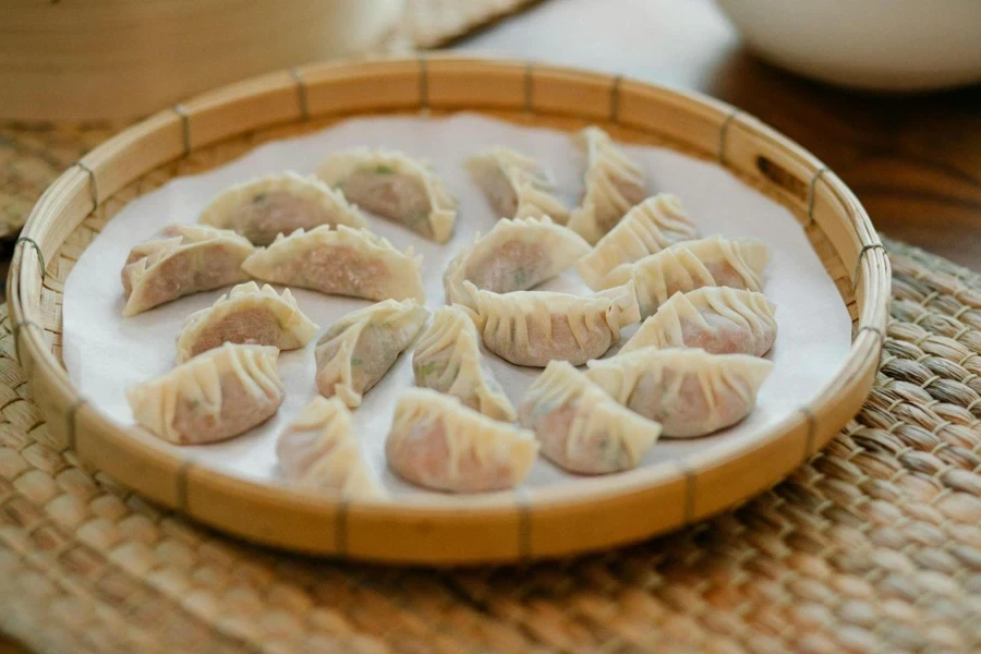 Fresh dumplings in bamboo tray on straw mat