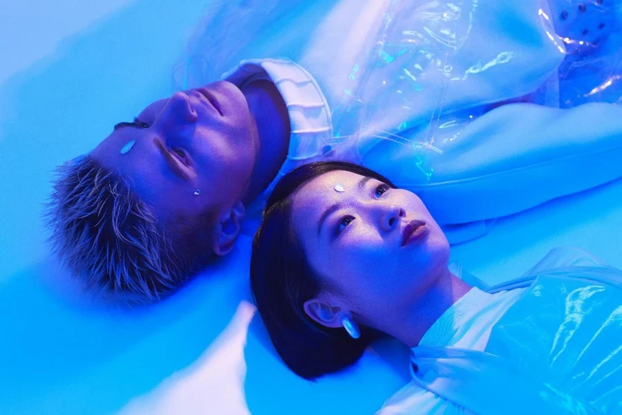 Futuristic Photo of a Young Man and Woman Lying on the Floor in Blue Lighting