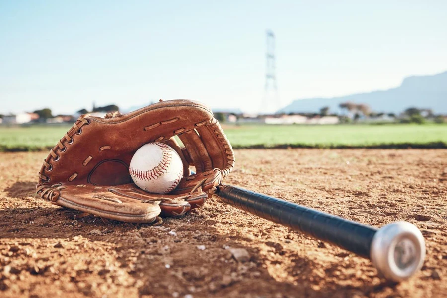 Glove, bat and baseball gear on the sand for a game, professional competition or sports