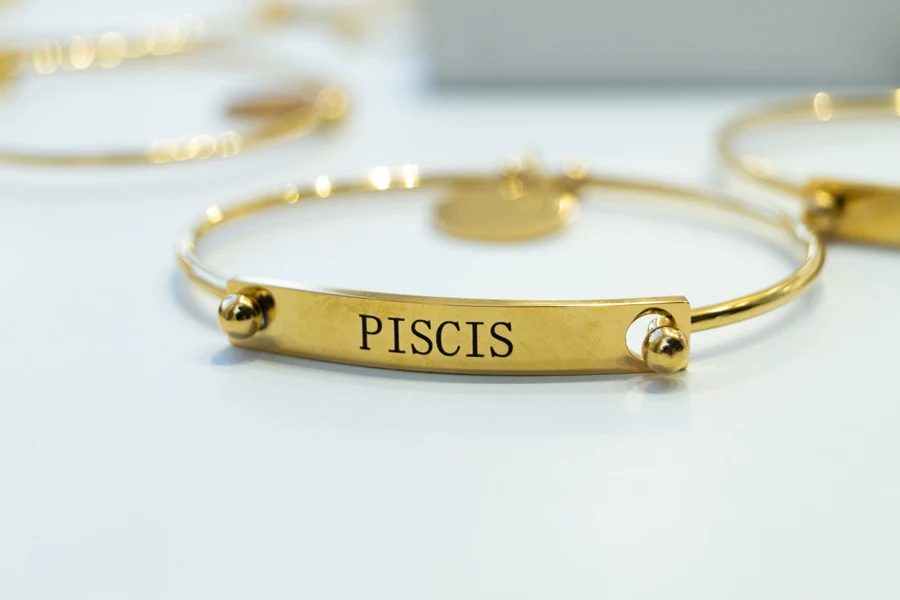 Gelang emas dengan tulisan Pisces dalam bahasa Spanyol