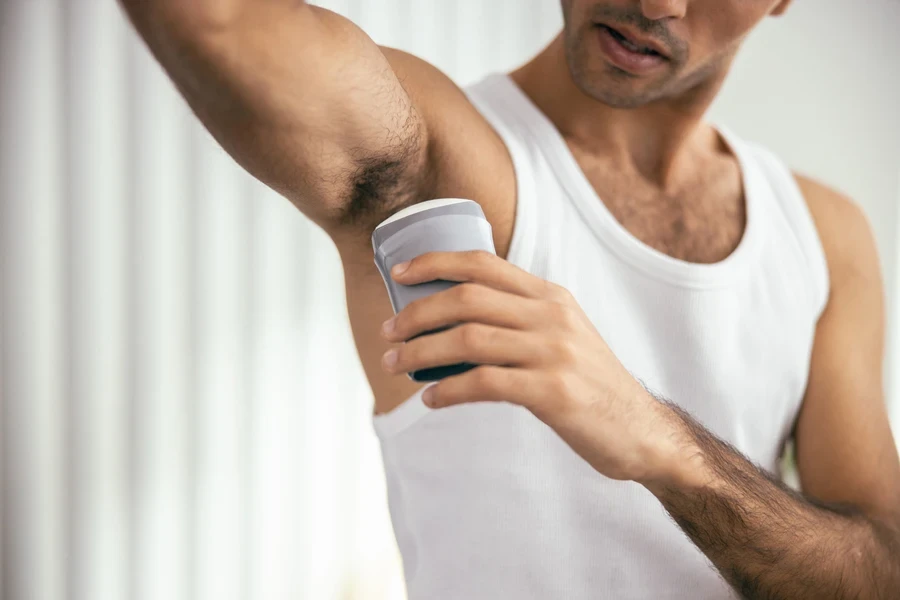 Guy in a T-shirt using a stick deodorant