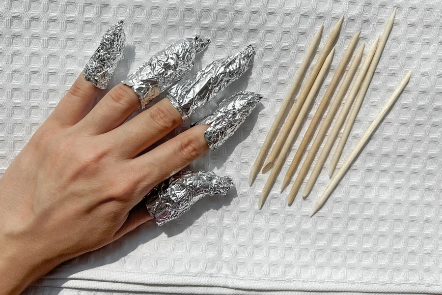 Hand with tin foil and cuticle sticks