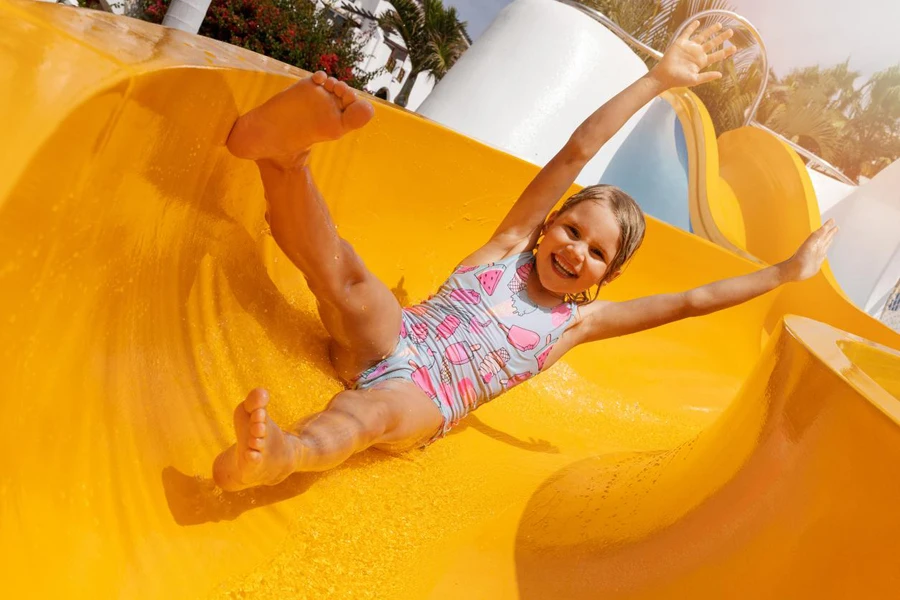 Happy child having fun on slide at outdoor water park.