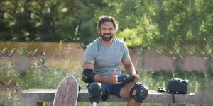 Man Wearing Elbow and Knee Pads Sitting on Concrete Bench