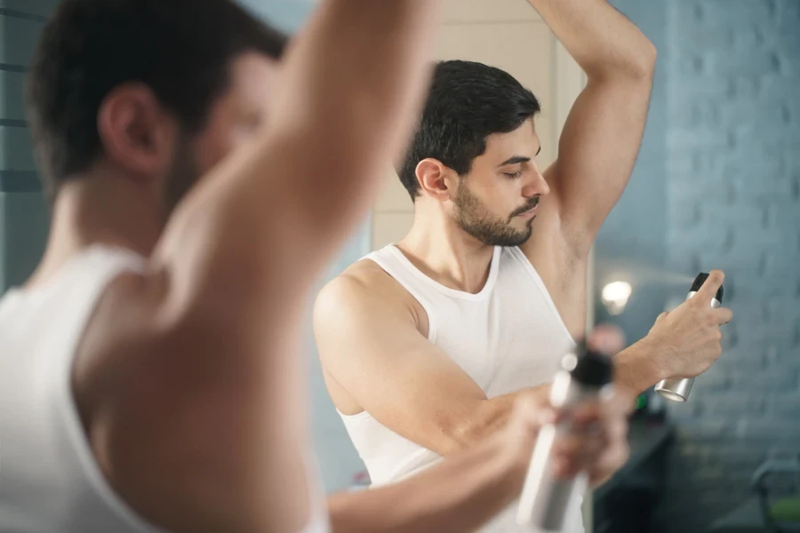 Man using spray deodorant on his underarm