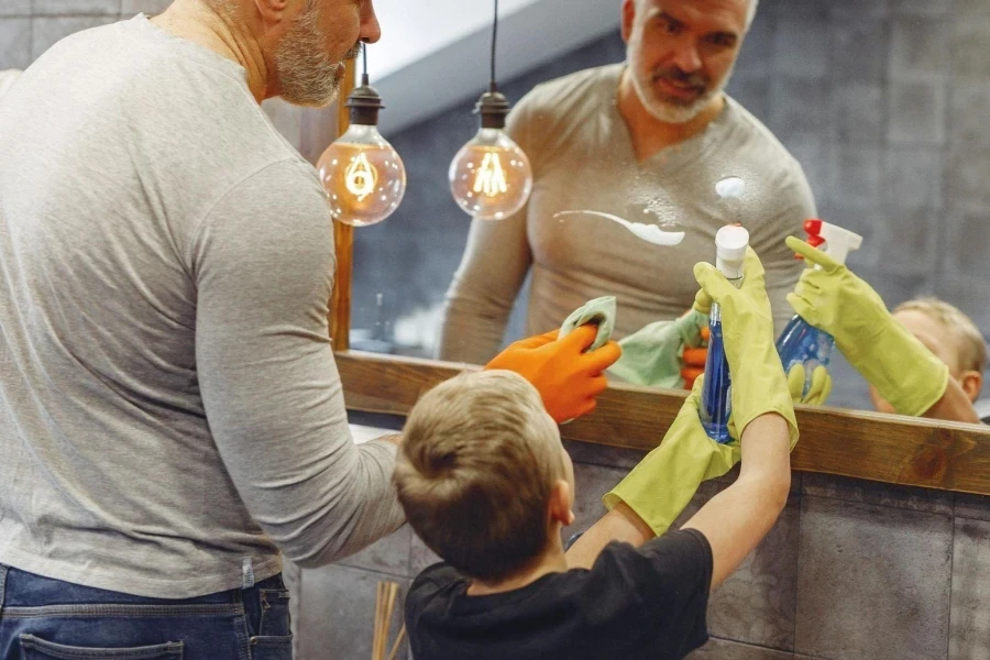 Man with Small Boy Cleaning Mirror in Bathroom